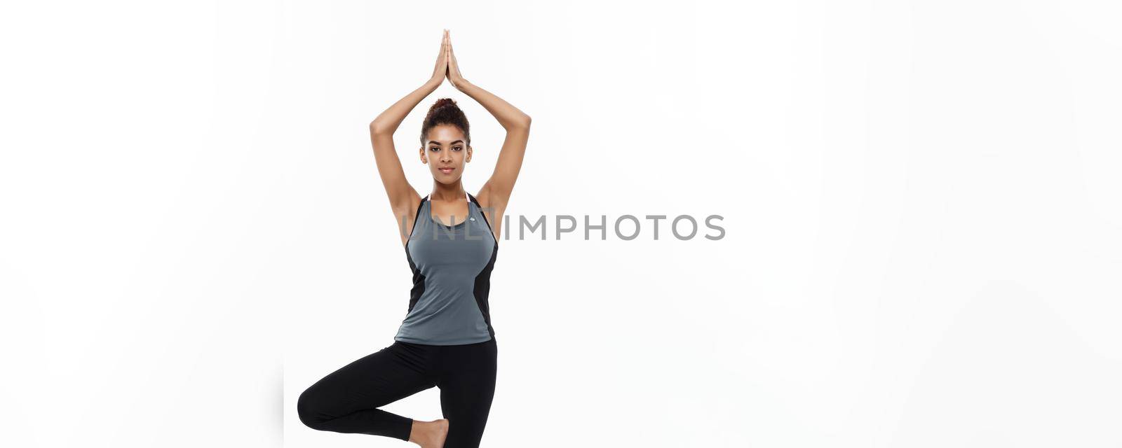 Healthy and Fitness concept - Beautiful American African lady in fitness clothing doing yoga and meditation. Isolated on white background