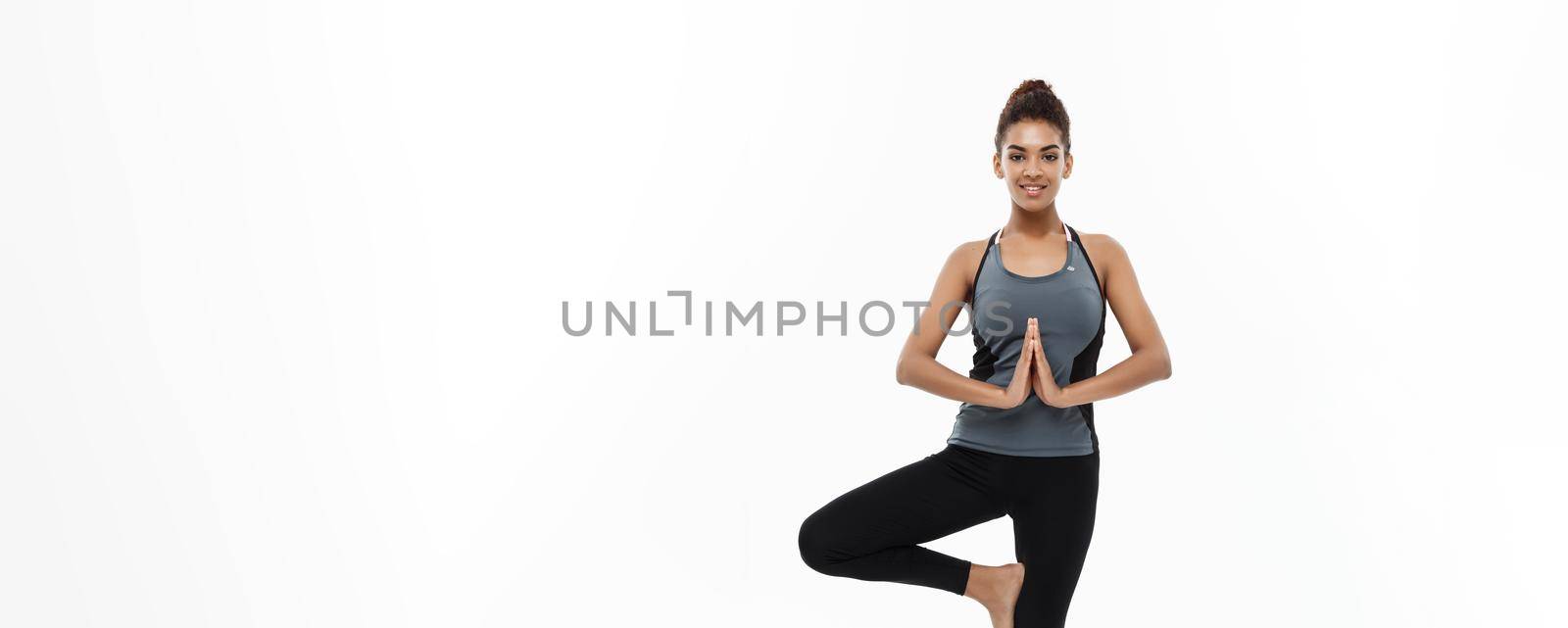 Healthy and Fitness concept - Beautiful American African lady in fitness clothing doing yoga and meditation. Isolated on white background