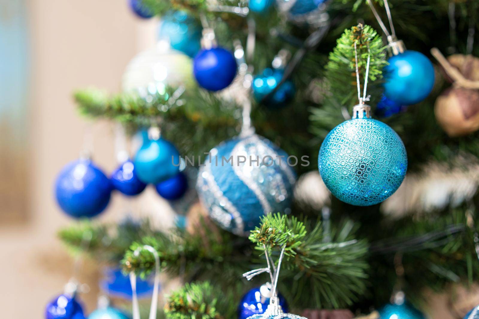 Bright Green Branch of New Year Tree. Christmas Tree Beautified with White and Blue Decorations. Beautiful New Year Balls. Selective focus on blue ball. Close up shot by LipikStockMedia