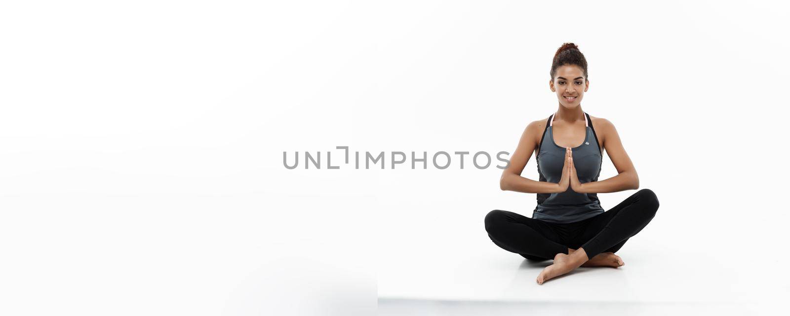 Healthy and Fitness concept - Beautiful American African lady in fitness clothing doing yoga and meditation. Isolated on white background. by Benzoix