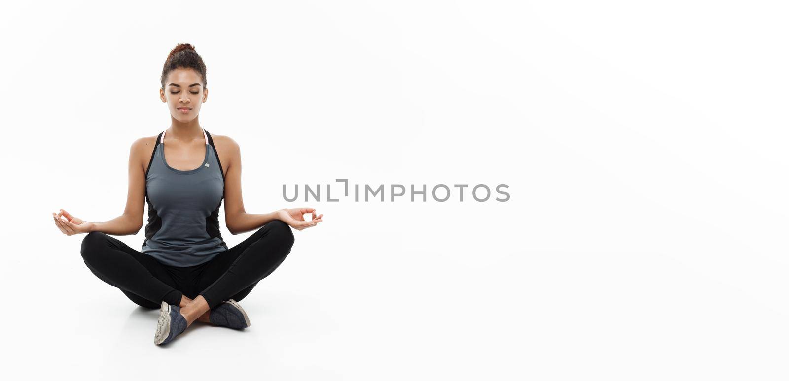 Healthy and Fitness concept - Beautiful American African lady in fitness clothing doing yoga and meditation. Isolated on white background