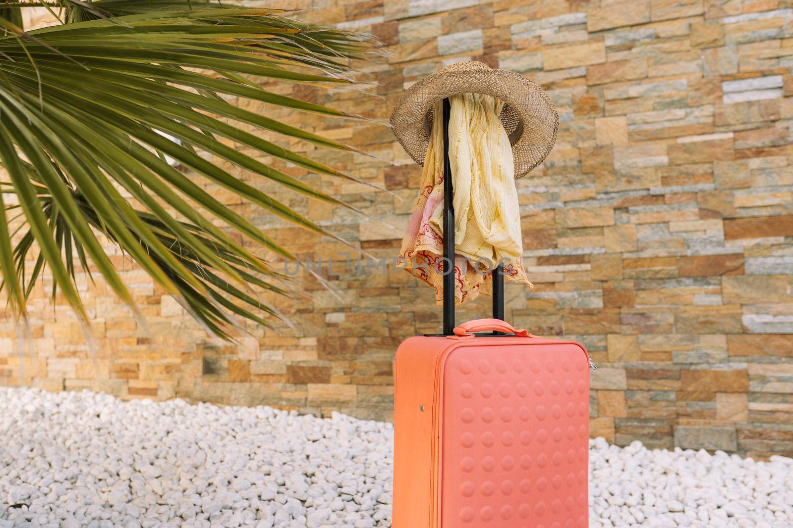 luggage in front of a stone wall and grass floor to use text. suitcase with hat and sunglasses. graphic resource. copy space.