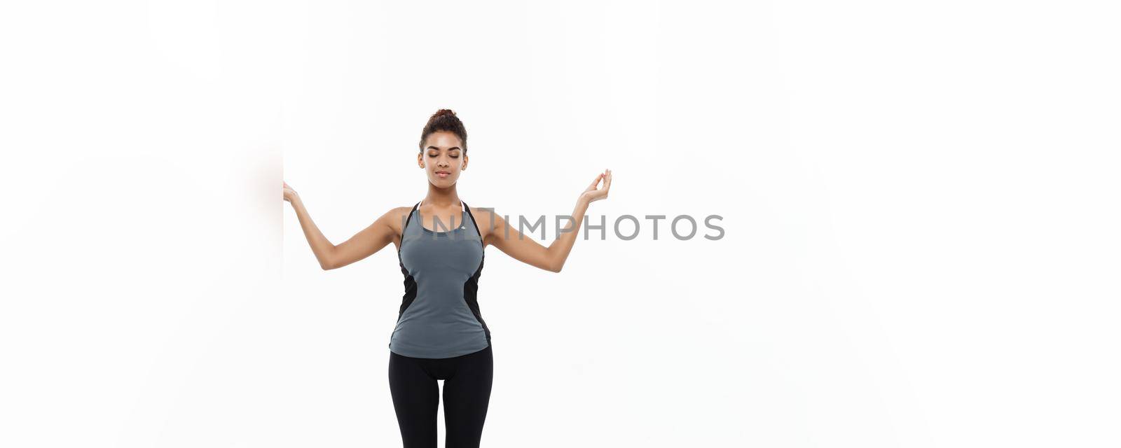 Healthy and Fitness concept - Beautiful American African lady in fitness clothing doing yoga and meditation. Isolated on white background. by Benzoix