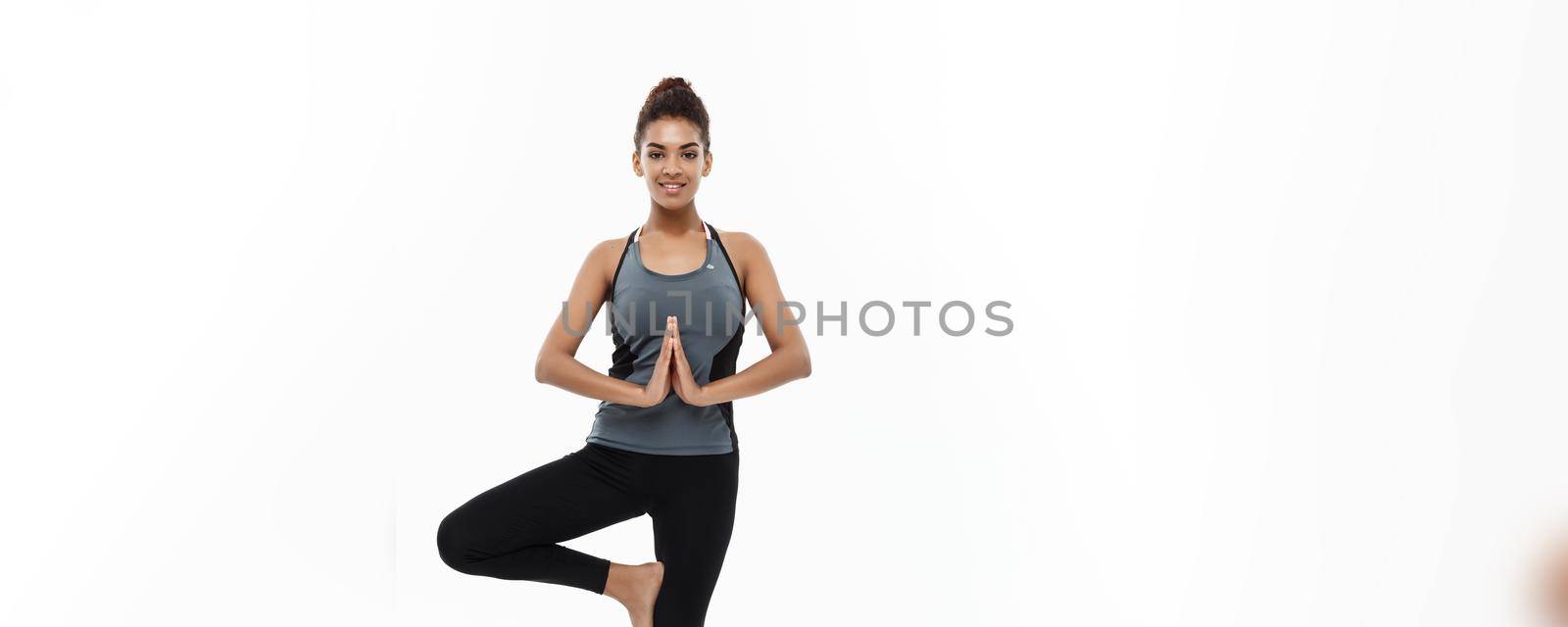 Healthy and Fitness concept - Beautiful American African lady in fitness clothing doing yoga and meditation. Isolated on white background. by Benzoix