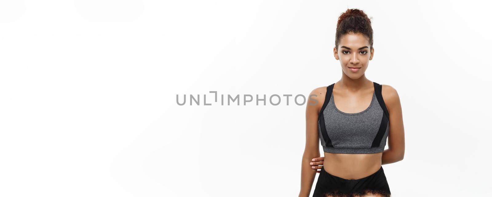 Healthy and Fitness concept - Beautiful American African lady in fitness clothes ready for workout. Isolated on white background. by Benzoix