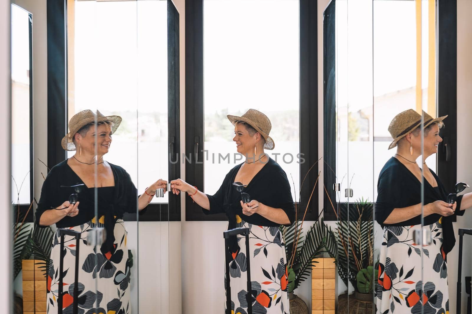 adventurous mature woman, arriving at the hotel room from her summer holiday. woman unpacking her luggage in the dressing room. by CatPhotography