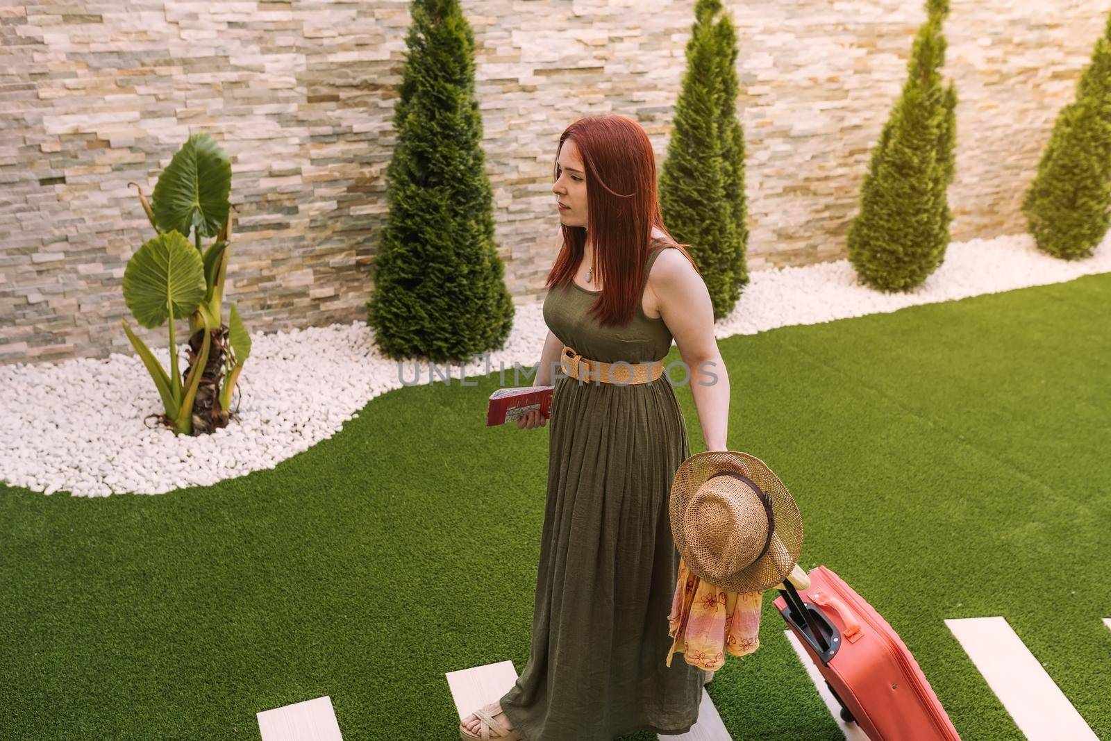 young girl arriving with her luggage at the reception of her summer holiday hotel. businesswoman arriving at her holiday destination. concept leisure and hobby. by CatPhotography