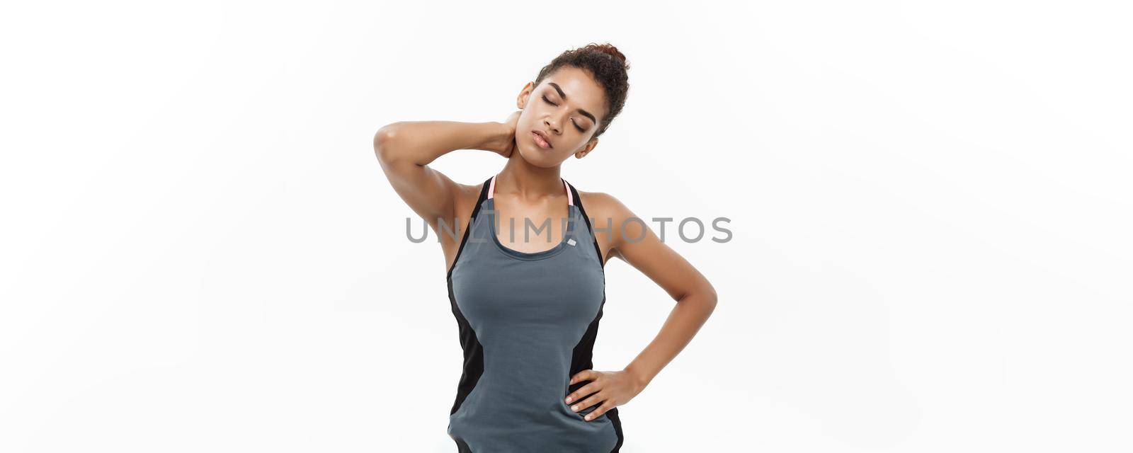 Healthy and Fitness concept - portrait of African American girl suffers a muscle injury standing holding her neck and lower back. Isolated on white background