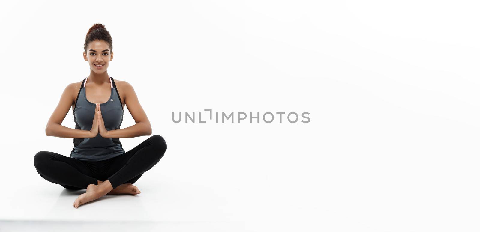 Healthy and Fitness concept - Beautiful American African lady in fitness clothing doing yoga and meditation. Isolated on white background. by Benzoix