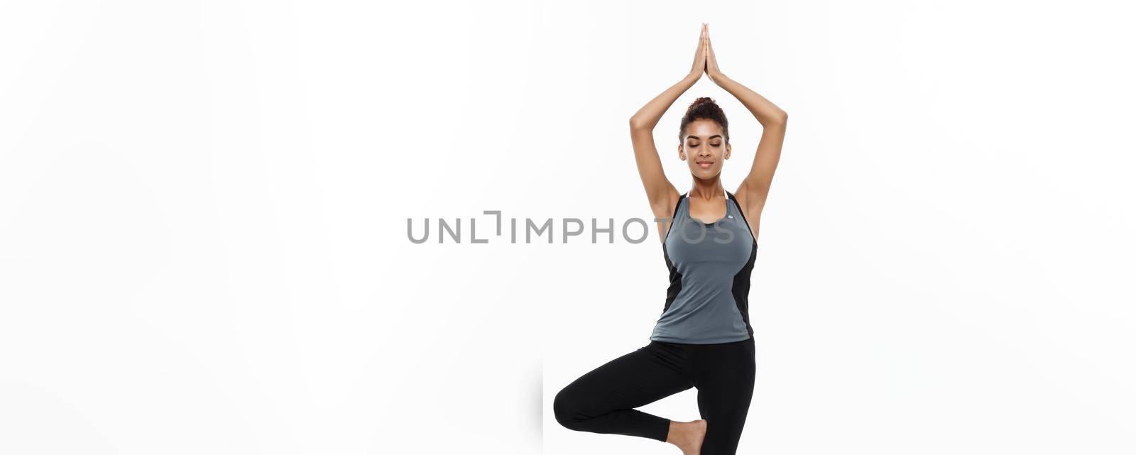 Healthy and Fitness concept - Beautiful American African lady in fitness clothing doing yoga and meditation. Isolated on white background. by Benzoix