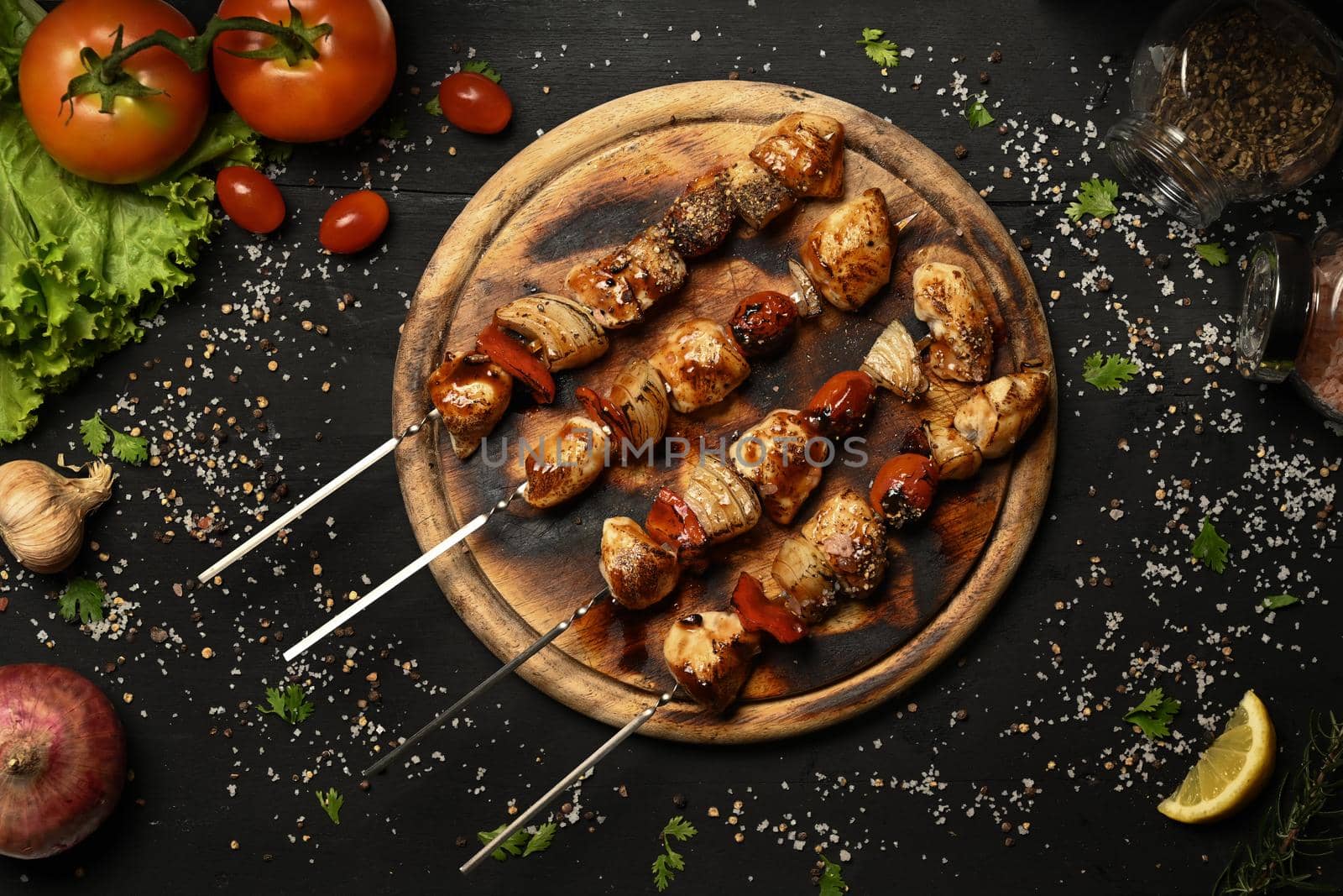 Above view grilled of chicken meat skewers cherry tomato and sweet pepper and onions in wooden plate. Barbecuing dinner.