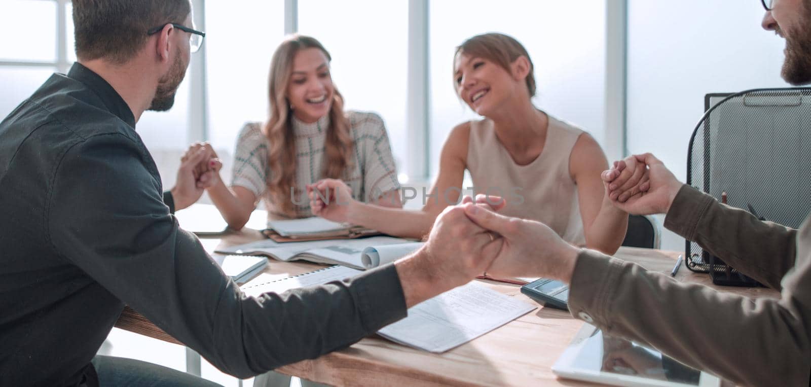 business team sitting at the table and showing their unity by asdf