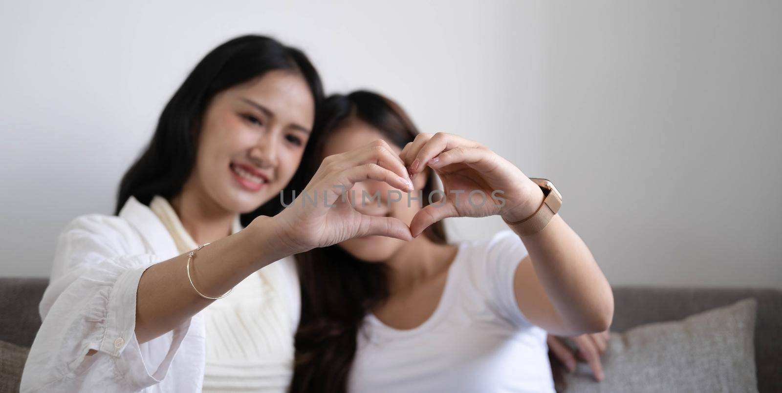 Happy LGBT lesbian couple holding hands in shape of heart..