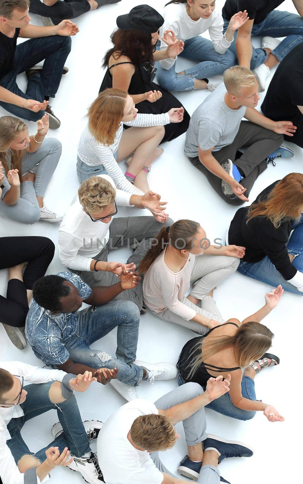 casual group of young people meditating sitting on the floor. by asdf