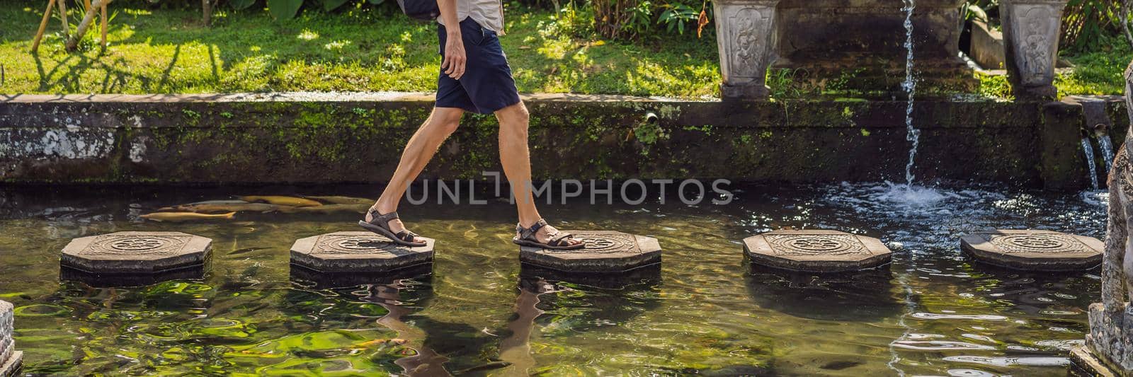 Young man tourist in Taman Tirtagangga, Water palace, Water park, Bali Indonesia. BANNER, LONG FORMAT