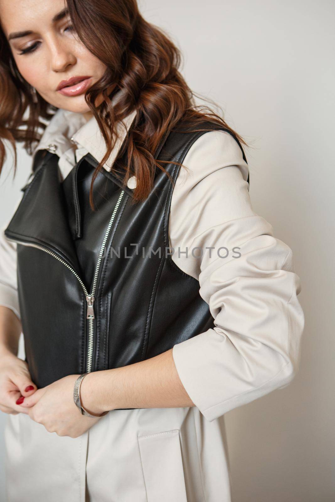 A model girl stands on a studio background, advertising clothes. A girl in a beige suit and a leather jacket by deandy