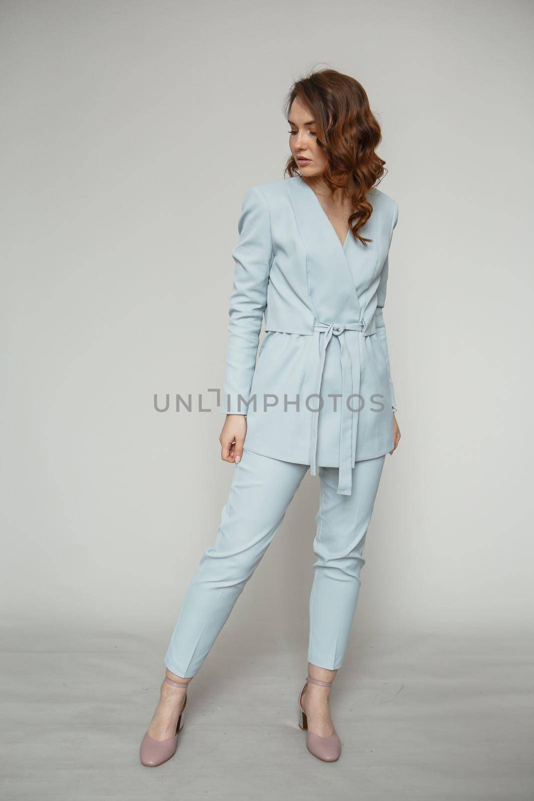 A model in a blue pantsuit on a studio background.