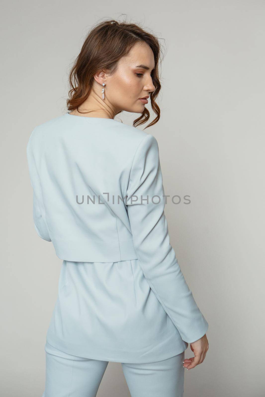 A model in a blue pantsuit on a studio background.