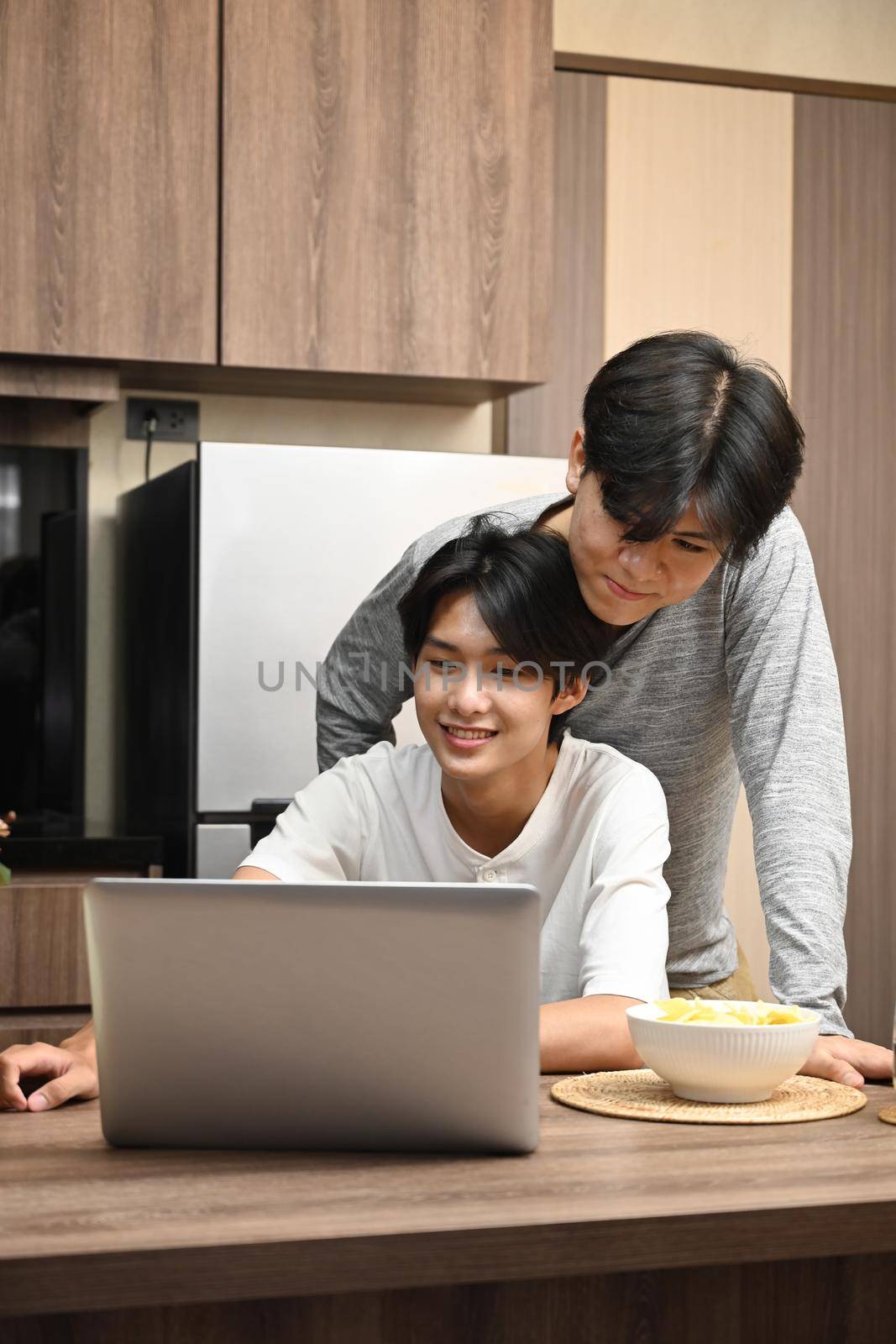 Loving male lgbt couple using laptop computer while spending time together at home. LGBT and love concept by prathanchorruangsak