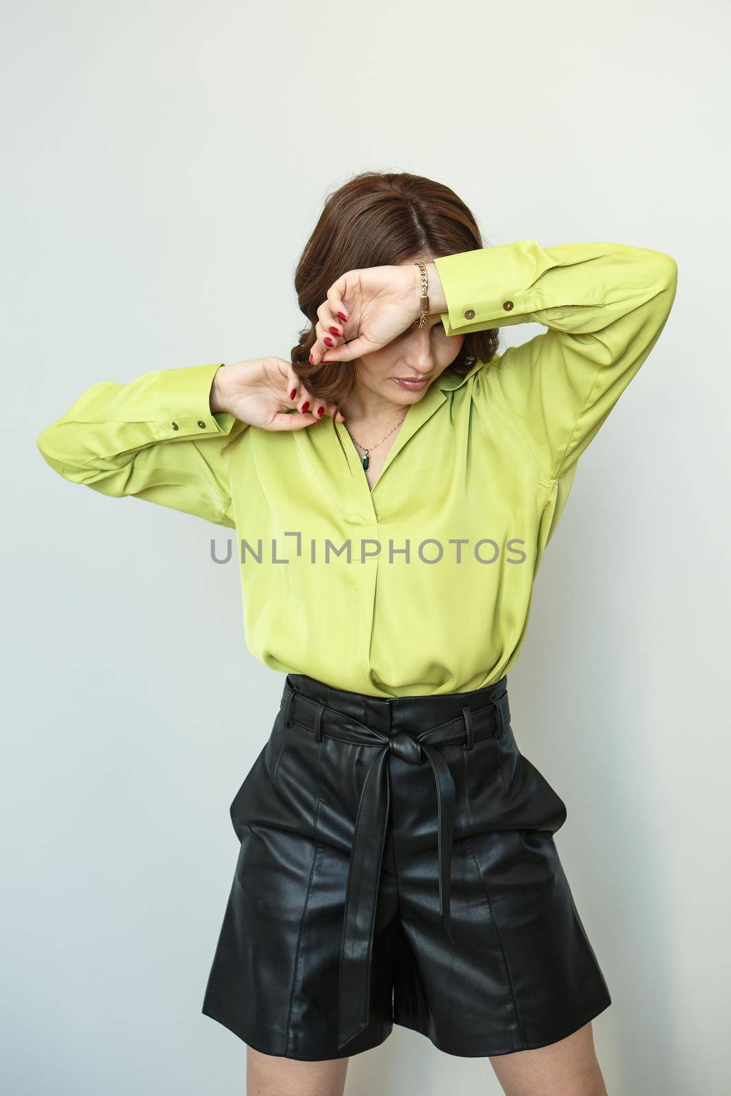 A model in light green clothes and black leather shorts. Shooting fashionable clothes for the showroom.