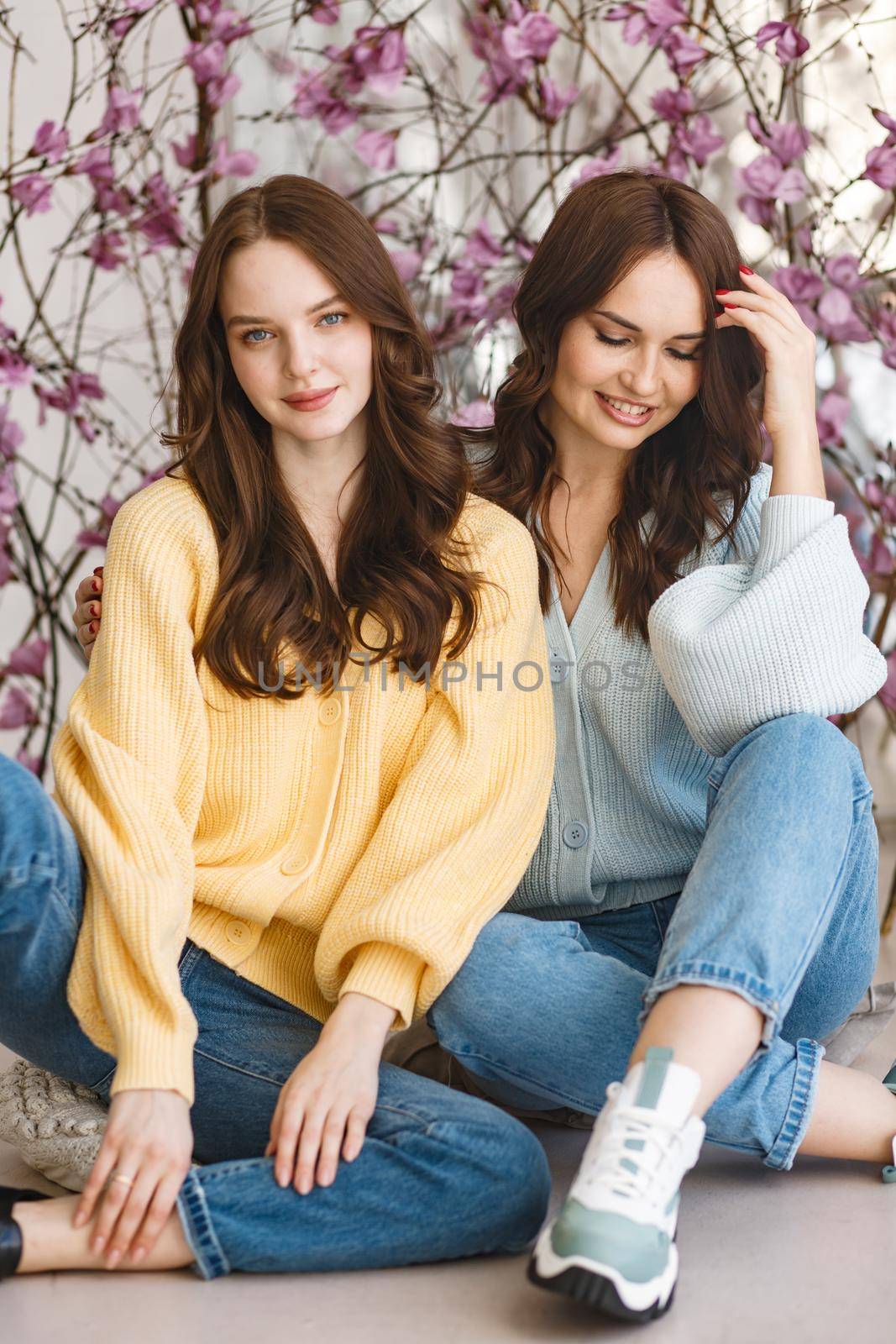 Two girls, models, have fun and smile in a photo studio.