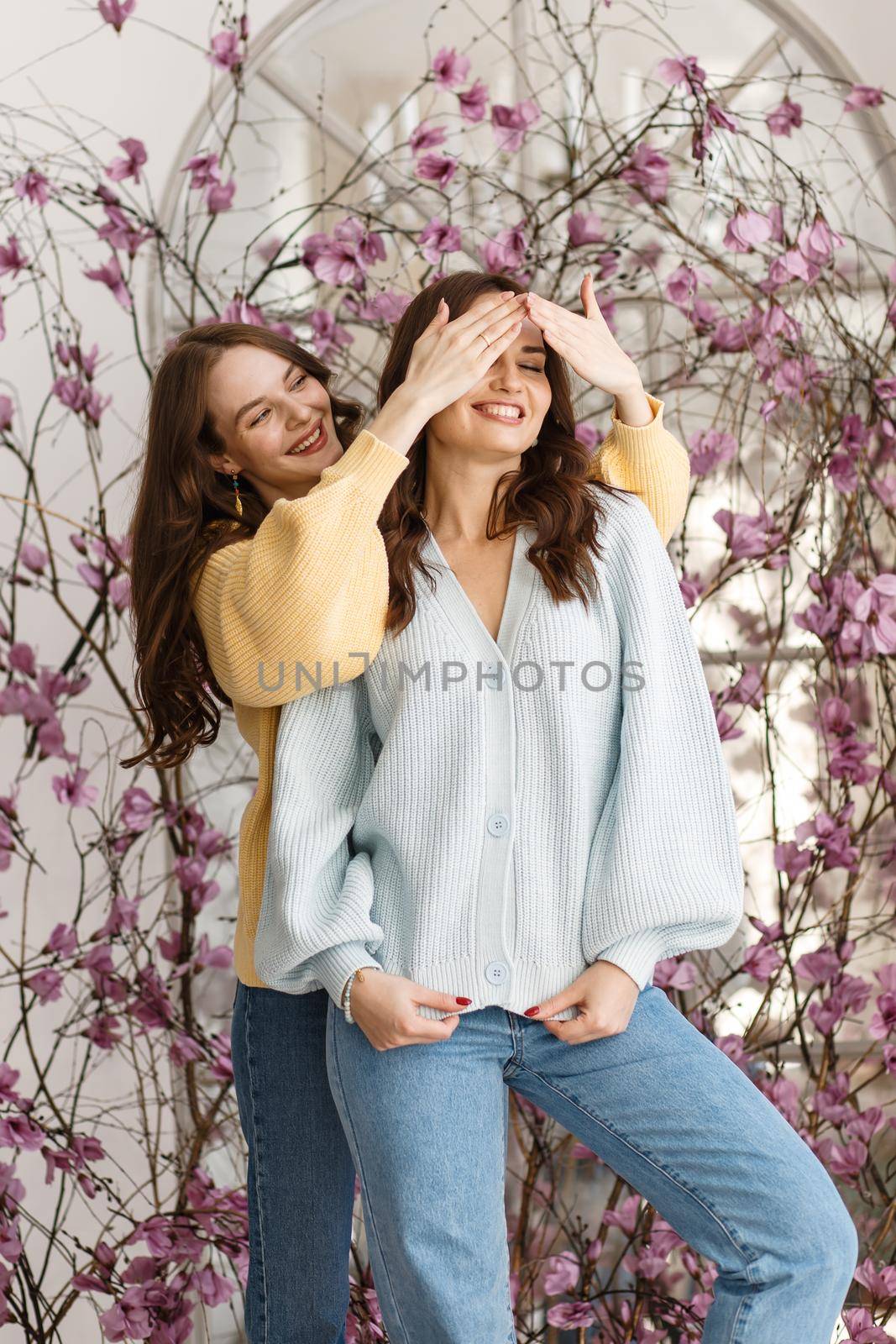 Two girls, models, have fun and smile in a photo studio.