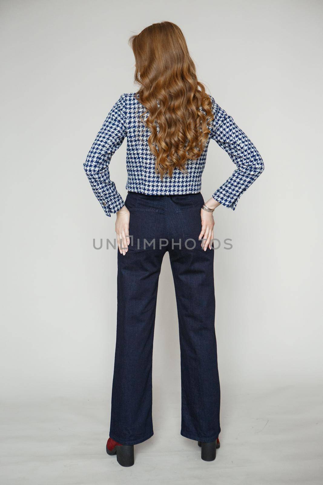 A girl in a denim suit standing on a studio background. A model in a blue suit