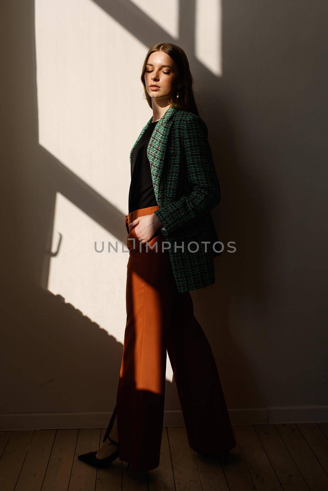 A model girl standing in the rays of the sun. the girl in the reflection of light from the window by deandy