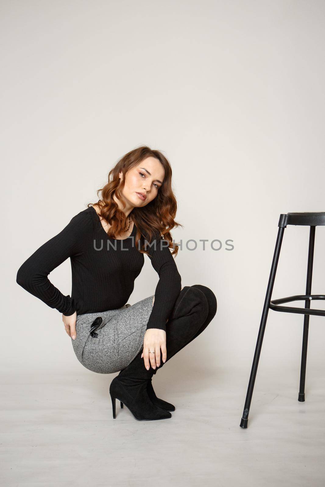 A girl in a black skirt photographed next to a black chair.