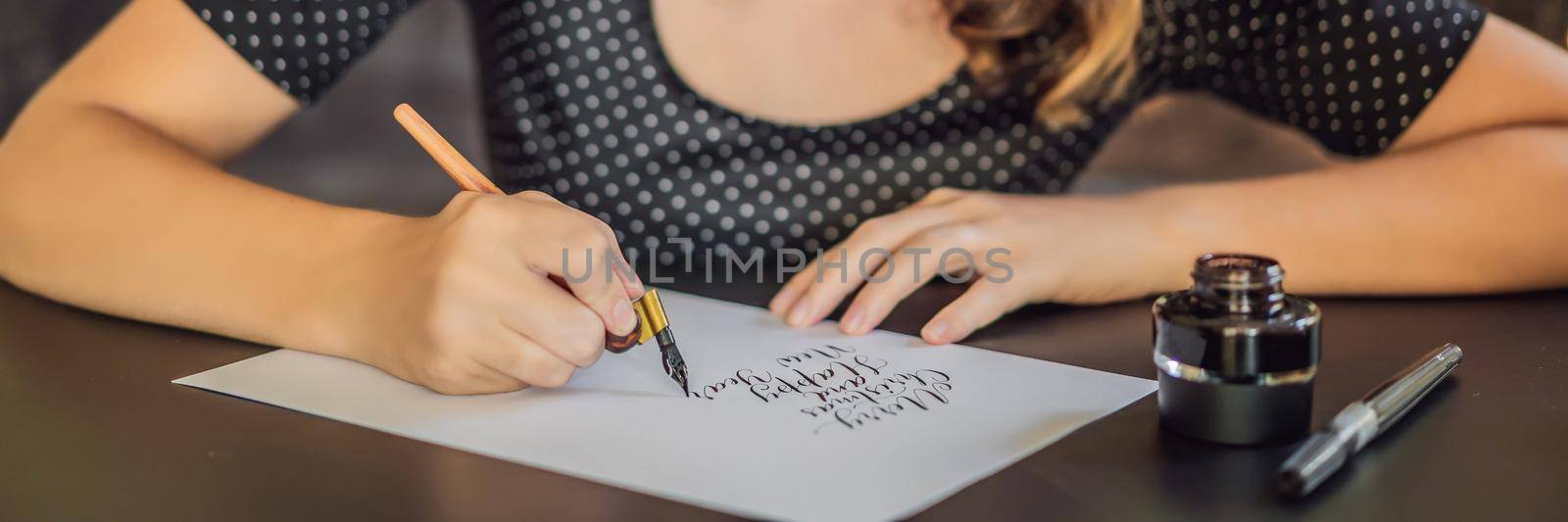 BANNER, LONG FORMAT Merry christmas and a happy new year. Calligrapher Young Woman writes phrase on white paper. Inscribing ornamental decorated letters. Calligraphy, graphic design, lettering, handwriting, creation concept.