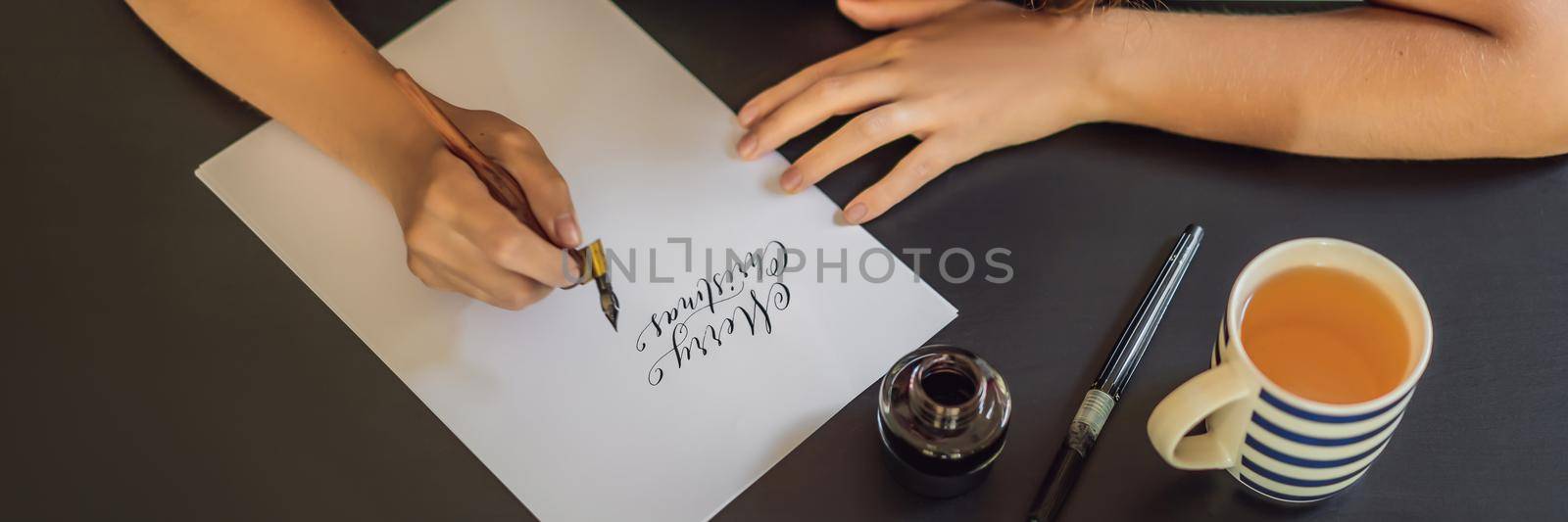 BANNER, LONG FORMAT Merry christmas and a happy new year. Calligrapher Young Woman writes phrase on white paper. Inscribing ornamental decorated letters. Calligraphy, graphic design, lettering, handwriting, creation concept by galitskaya