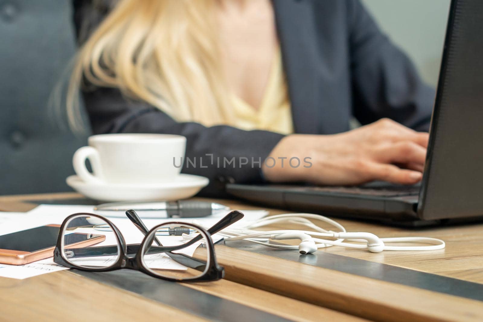 Eyeglass with coffee on office table on female business worker background.