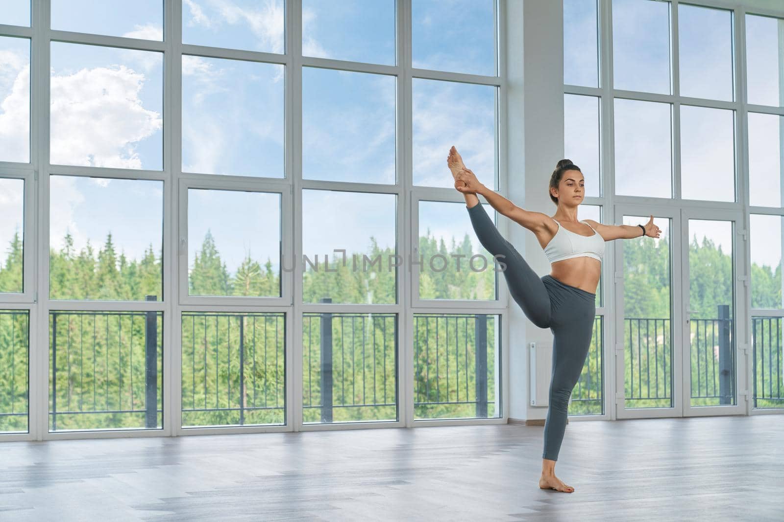 Active woman in sportswear stretching legs at hall by SerhiiBobyk