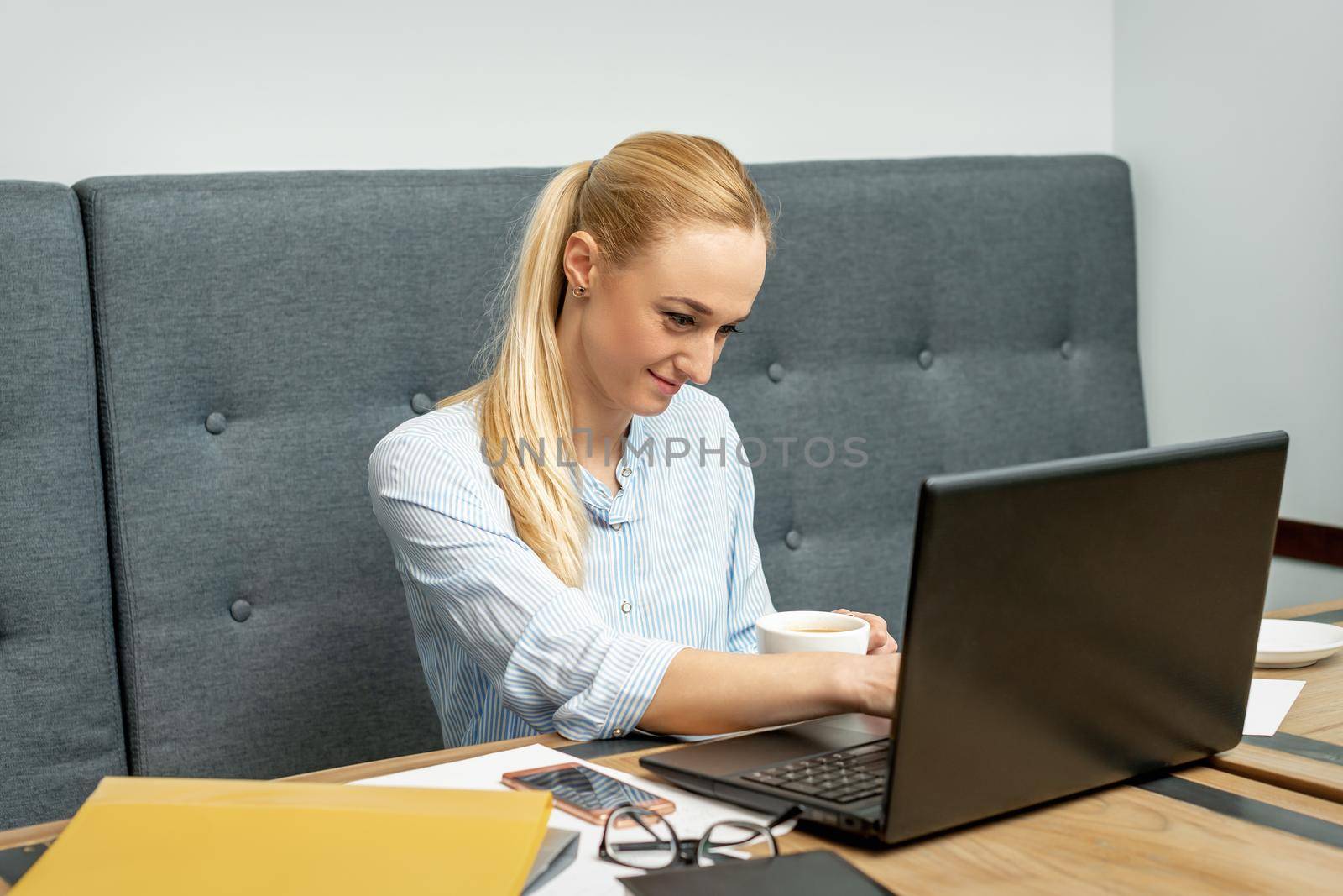 Woman is working on laptop at home office. by okskukuruza