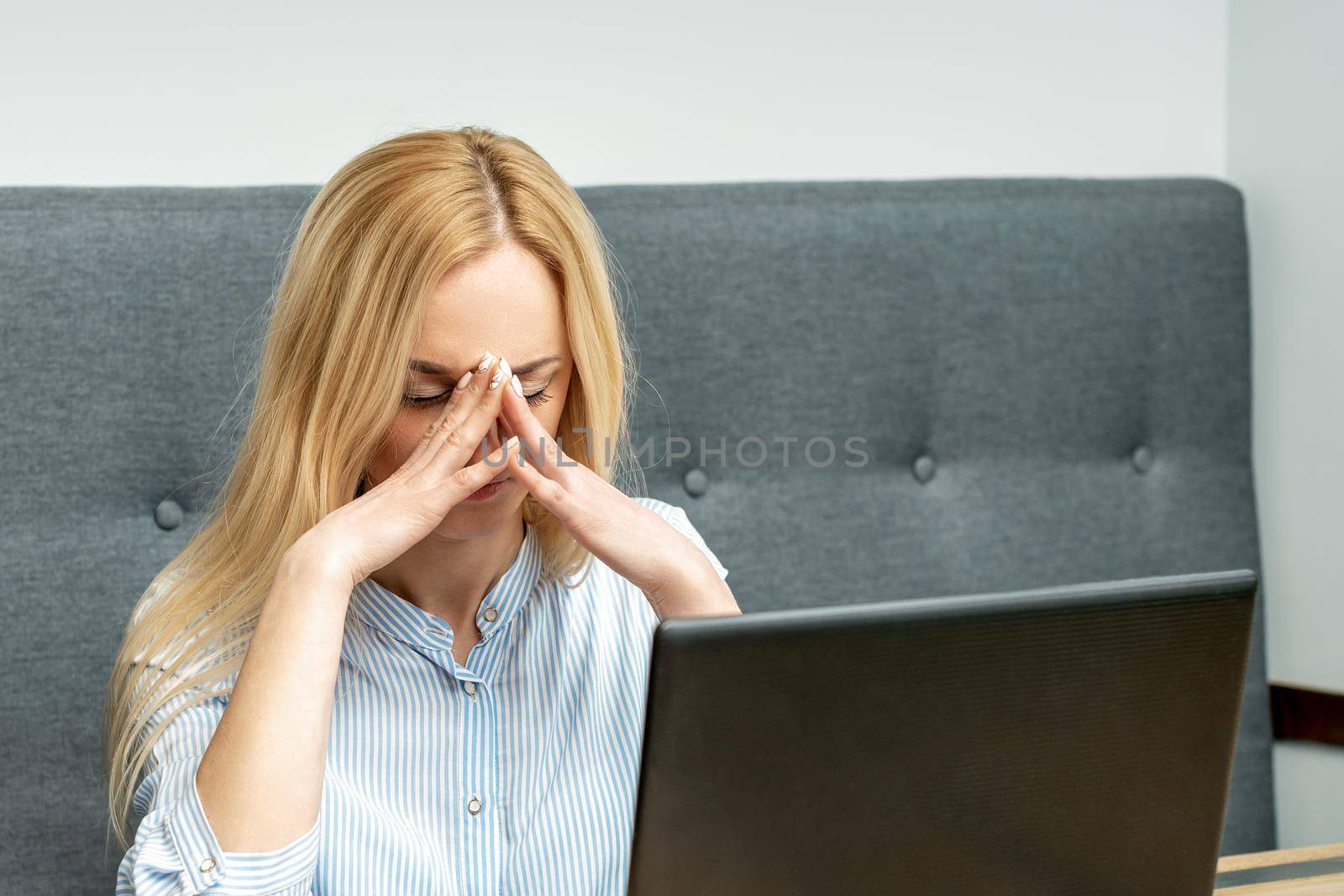 Tired young business woman sitting in front of laptop at office.