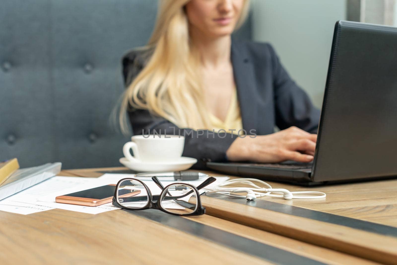 Eyeglass with coffee on office table on female business worker background.