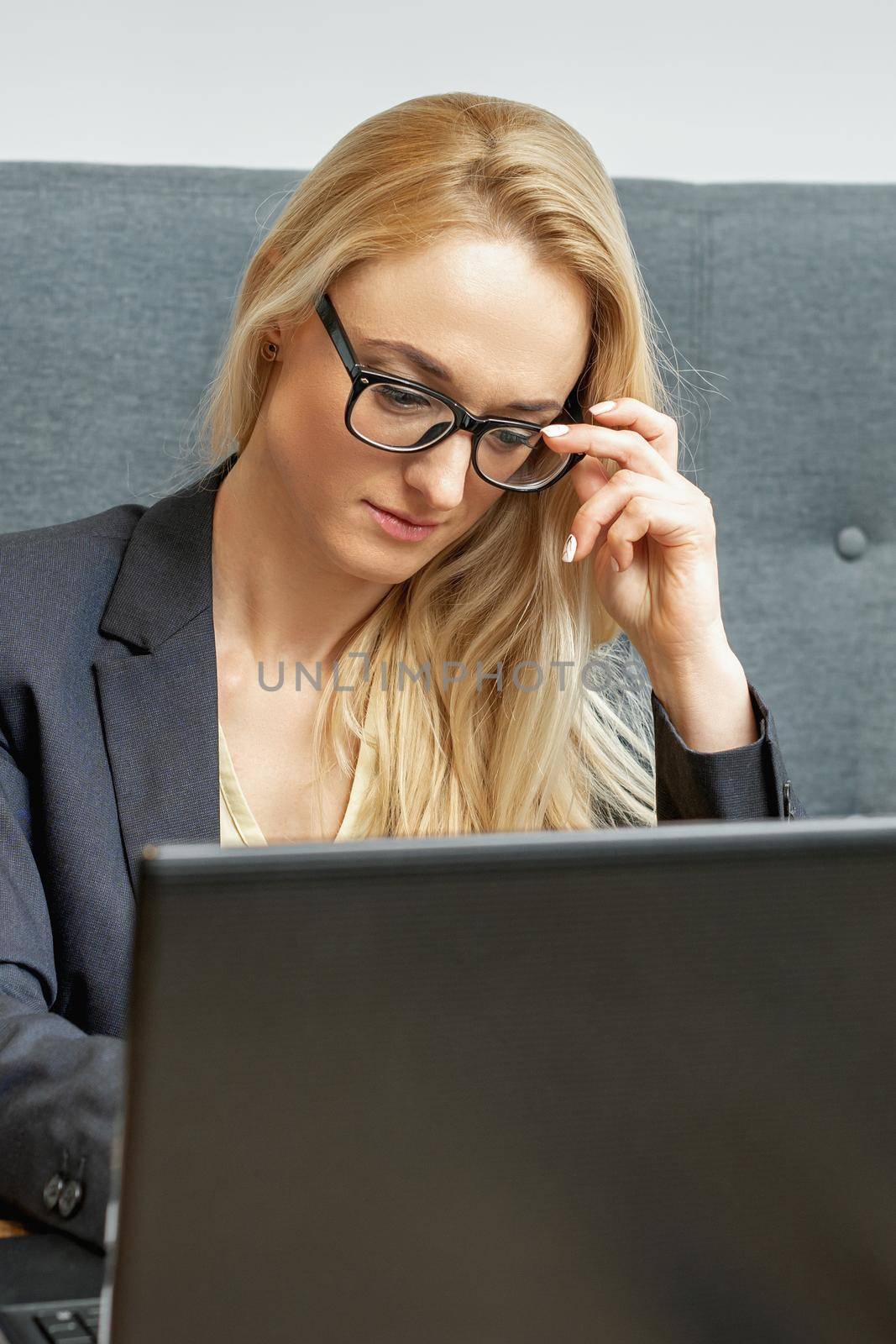 Busy business woman wearing eyeglasses working on laptop at home office.