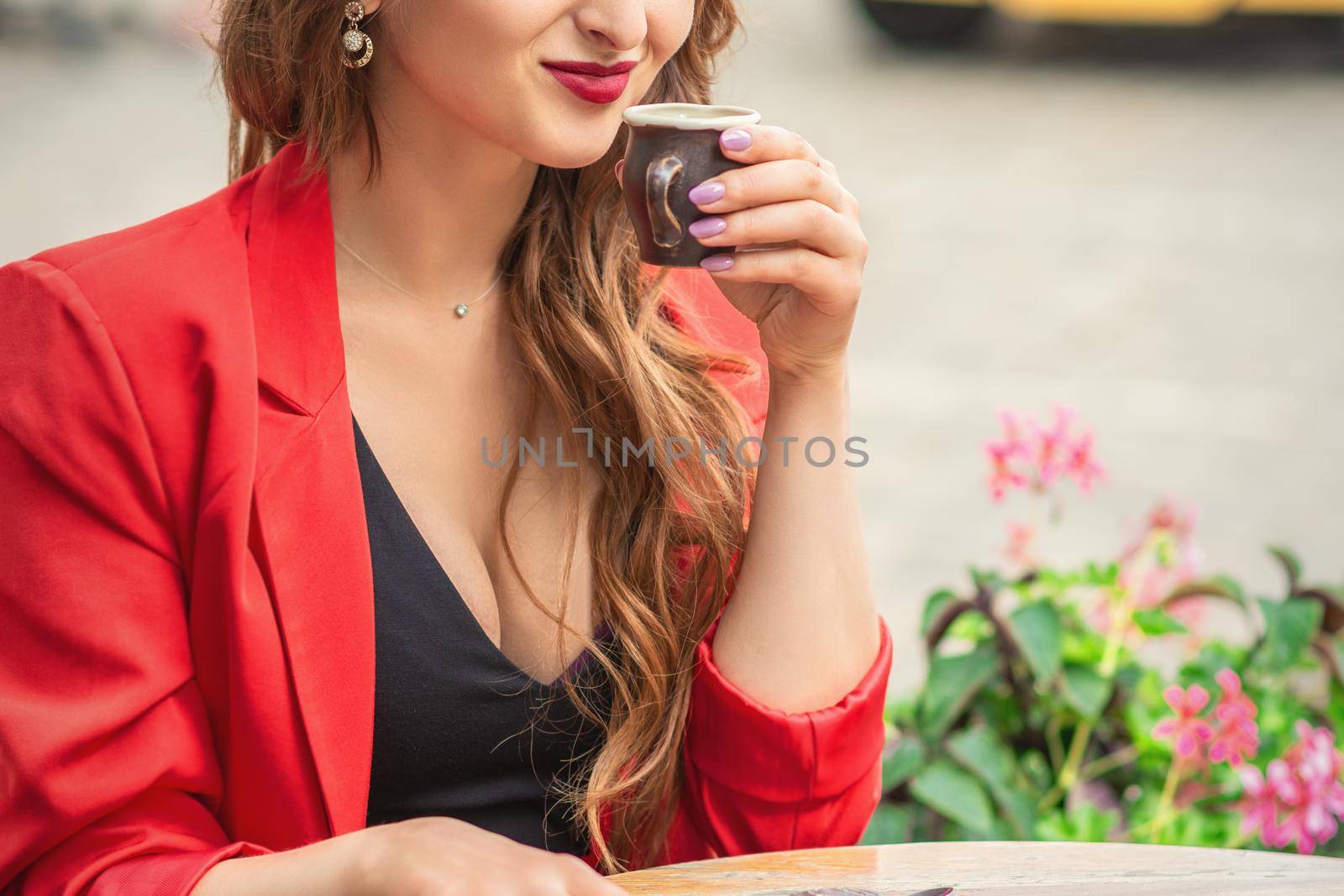 Portrait of young woman with cup drinking coffee at city street cafe.