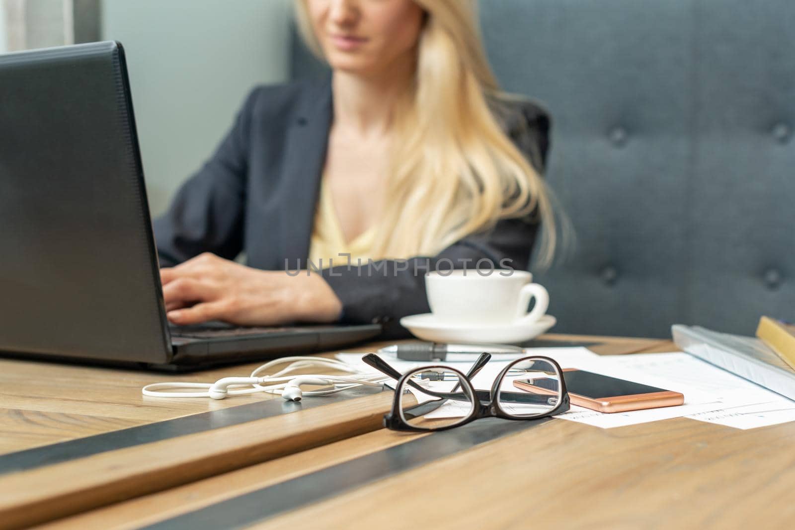 Eyeglass with coffee on office table on female business worker background.