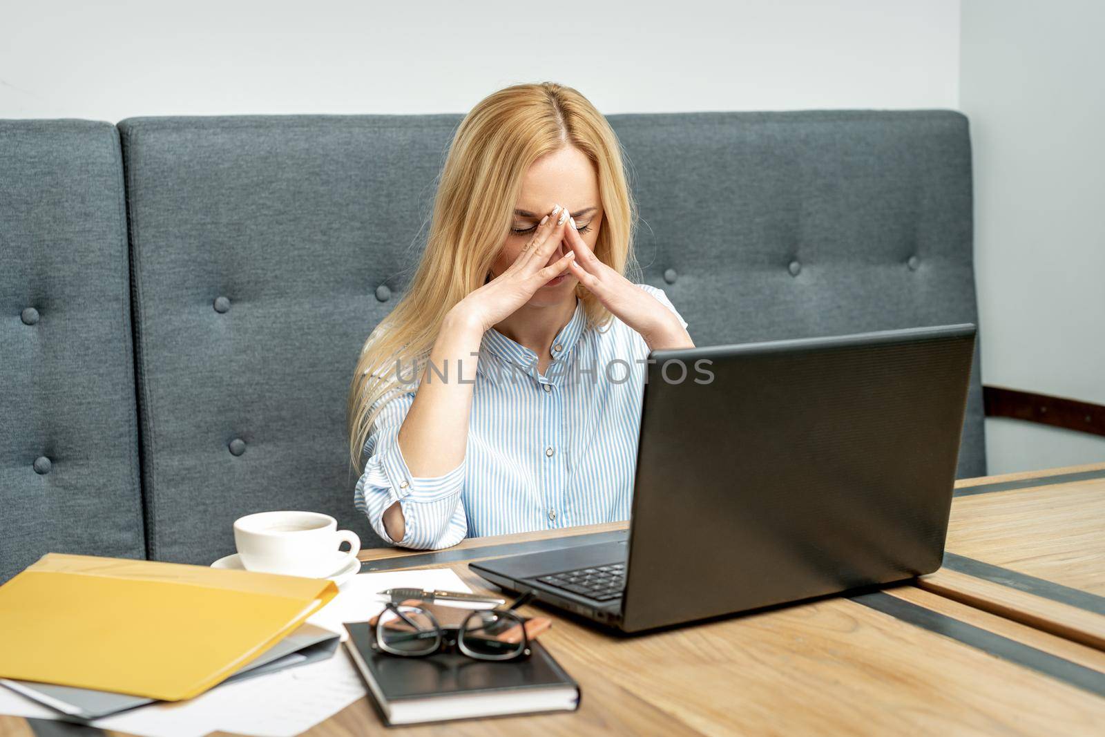 Tired young business woman sitting in front of laptop at office.