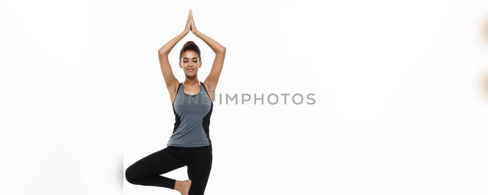 Healthy and Fitness concept - Beautiful American African lady in fitness clothing doing yoga and meditation. Isolated on white background