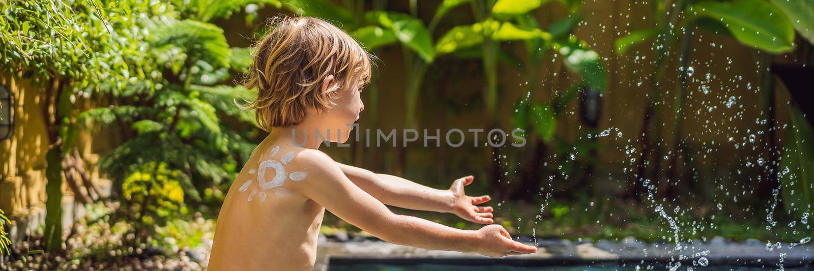 Happy boy with sun painted by sun cream on shoulder playing by the pool. Summer vacation concept. Space for text. BANNER, LONG FORMAT