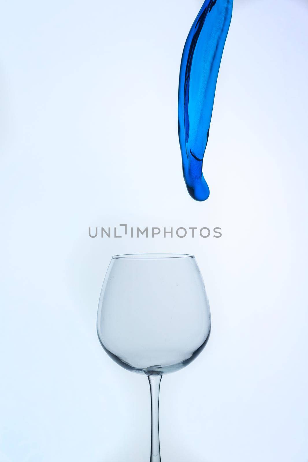 A splash of blue liquid in a glass on a white background. Cutout.
