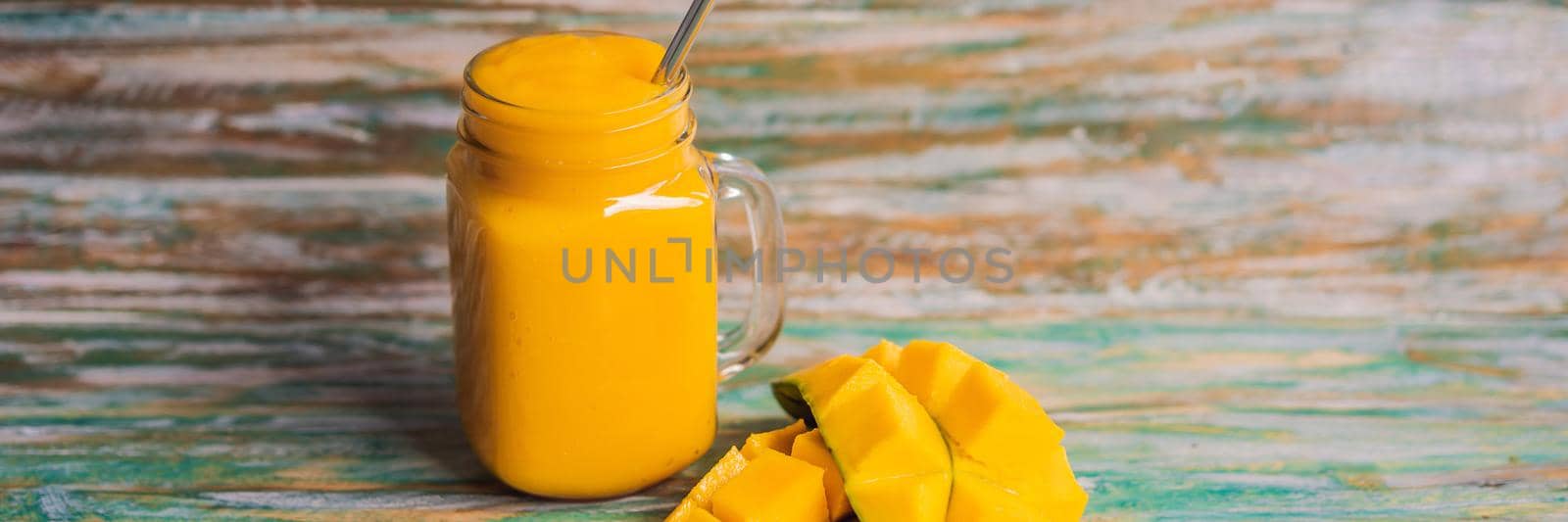 Mango smoothie and steel drinking straw on a painted wooden background BANNER, LONG FORMAT by galitskaya