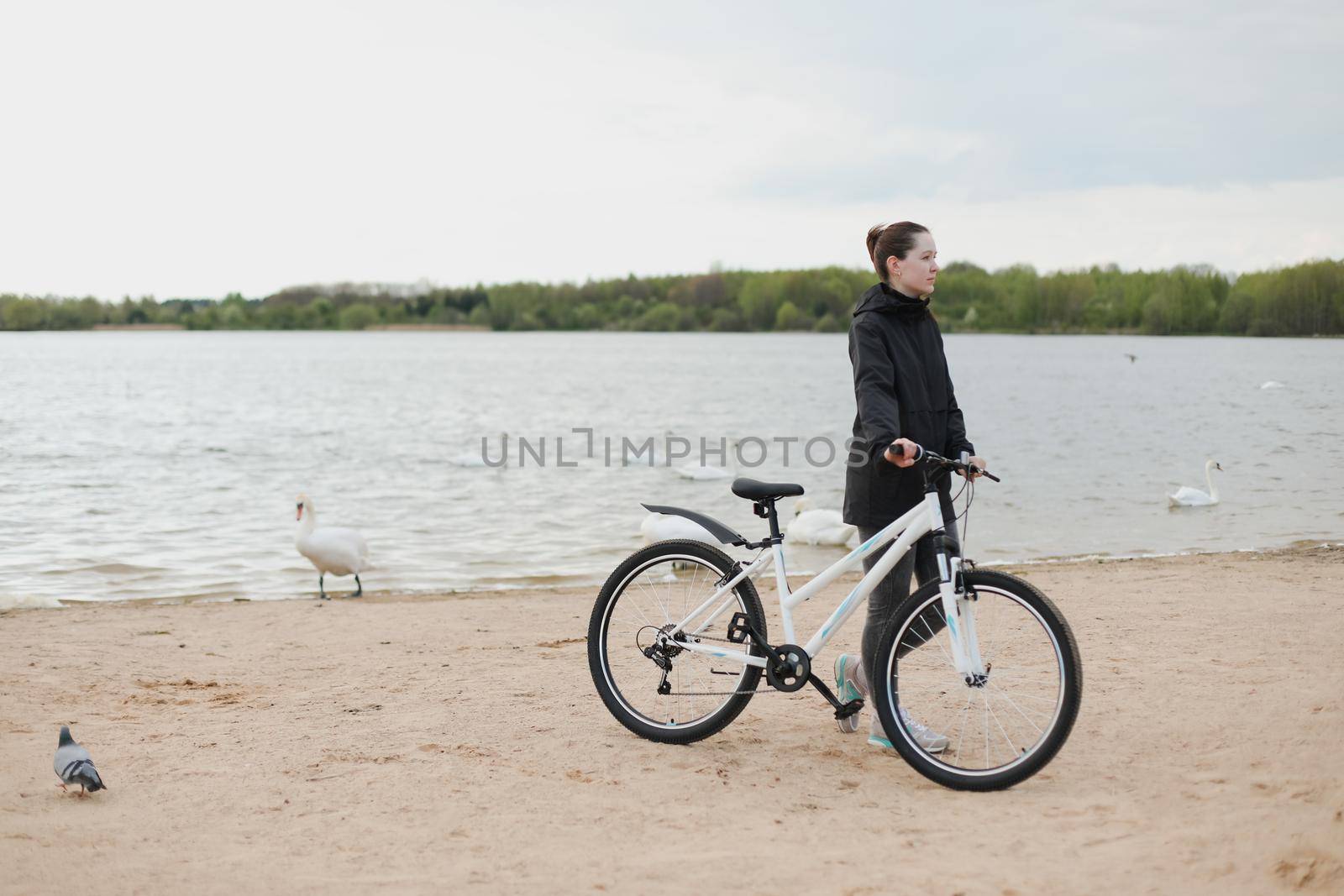 A young woman with a bicycle on the lake.