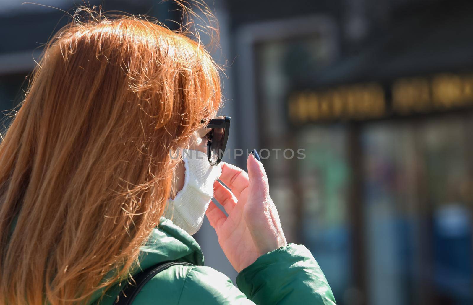 Man wearing facial hygiene mask outdoors. Virus protection, ecology, air pollution, environmental awareness concept. A woman on the street adjusts the mask on her face.