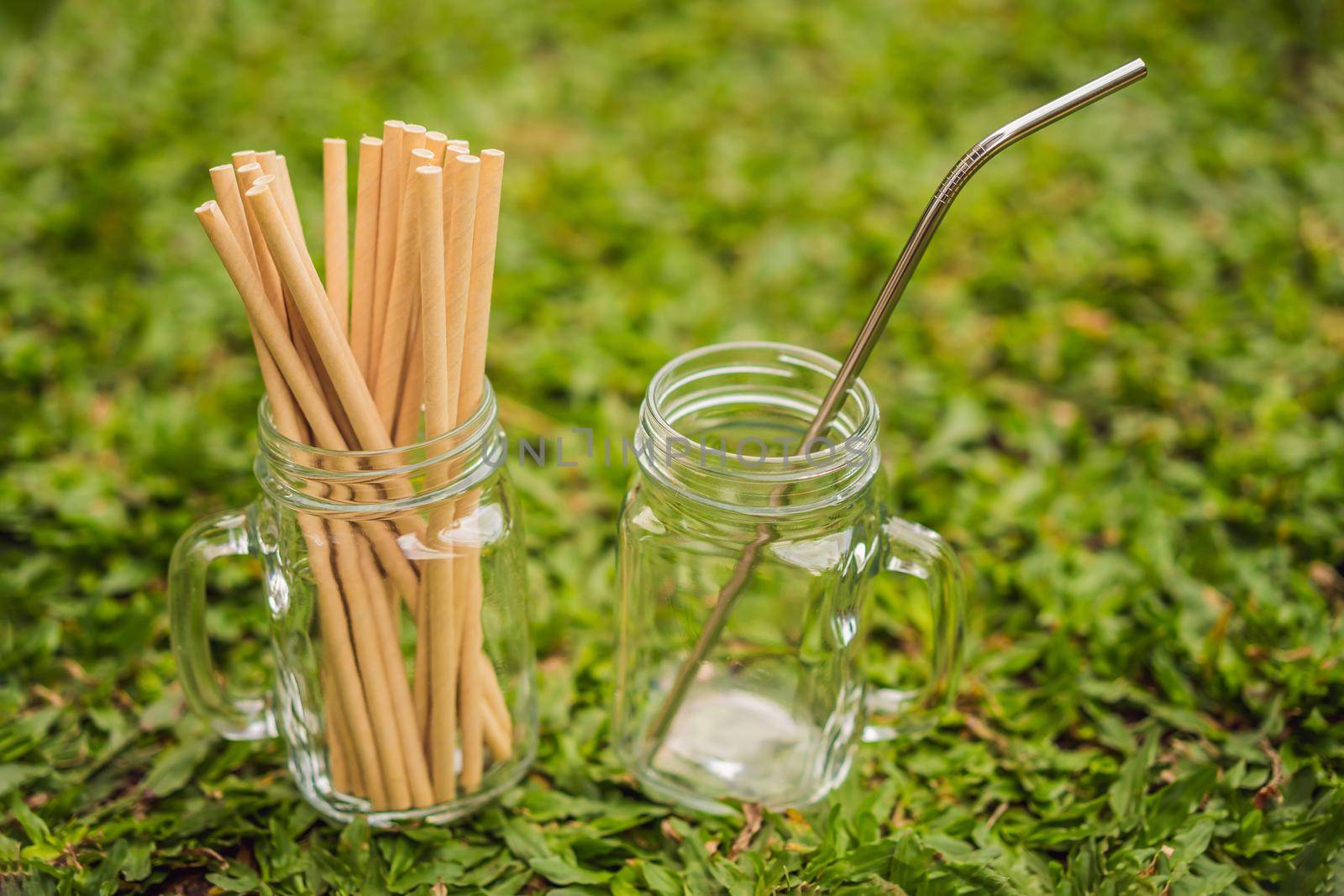 Steel drinking vs disposable straws on grass background. Zero waste concept.