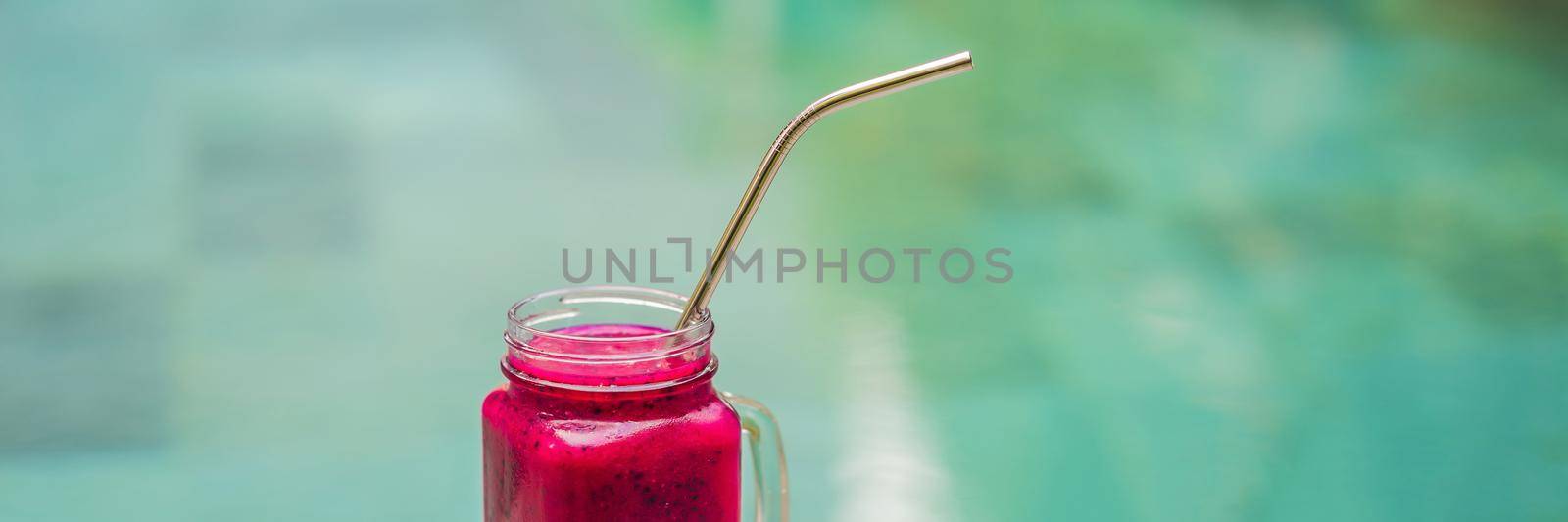 Dragon fruit smoothie with steel drinking straw on pool background. BANNER, LONG FORMAT