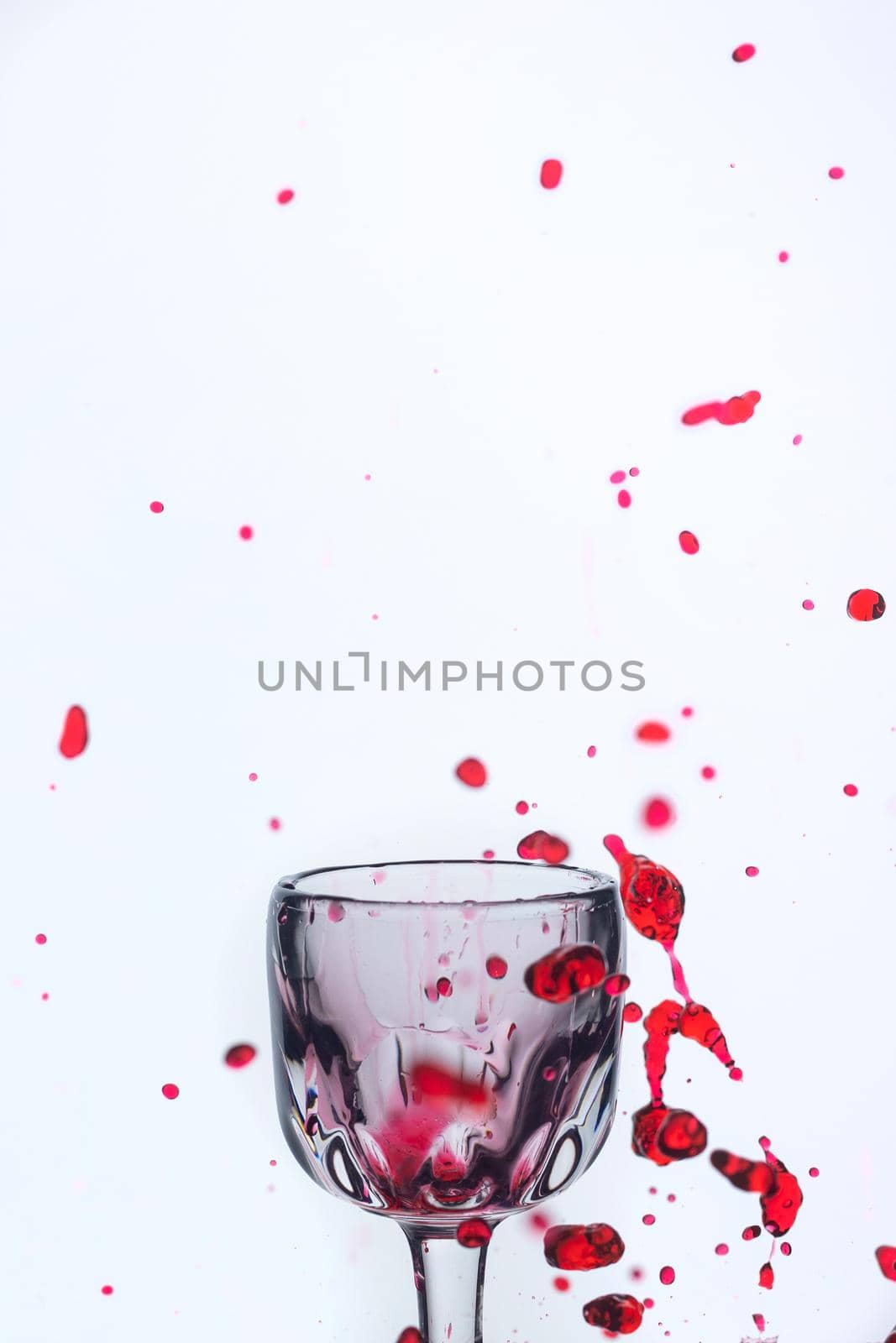 A splash of red wine in a glass on a white background. Cutout.