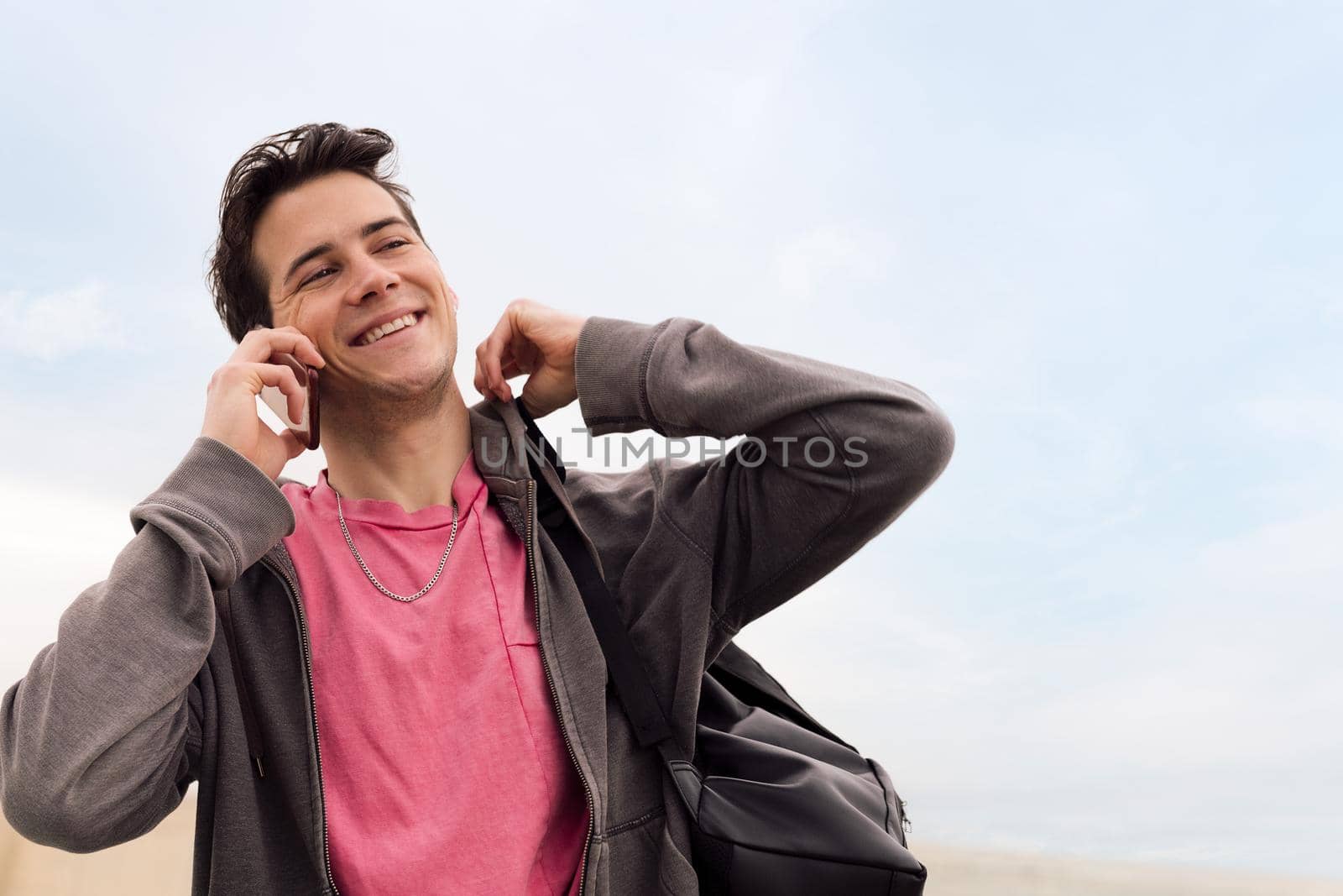 smiling happy young man talking on mobile phone, concept of communication and urban lifestyle, copy space for text